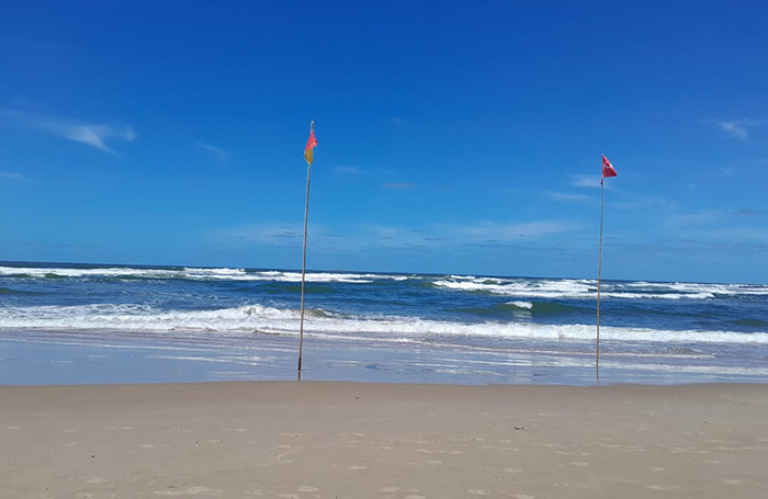 Beach with lifeguard flags waving, highlighting lifeguard duty on a sunny day. Beach with lifeguard flags waving, highlighting lifeguard duty on a sunny day.