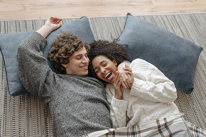 Couple laughing on the floor with pillows, illustrating shared hobbies and relationships. Couple laughing on the floor with pillows, illustrating shared hobbies and relationships.