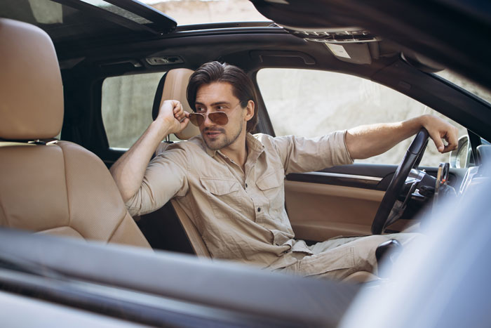Man in sunglasses confidently seated in a car, appearing thoughtful, representing theme of food bank and income deception. Man in sunglasses confidently seated in a car, appearing thoughtful, representing theme of food bank and income deception.