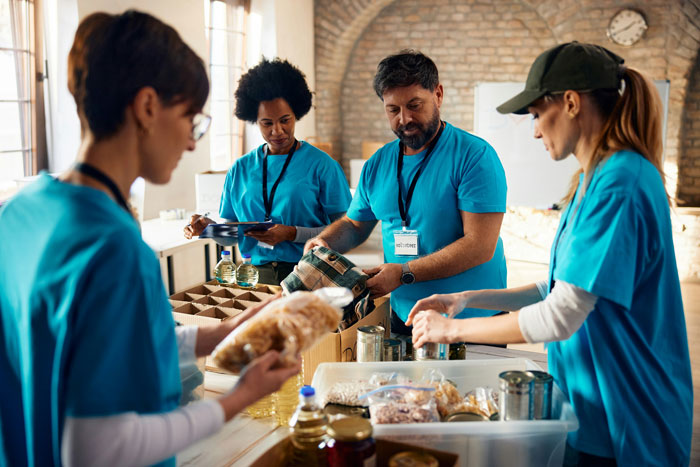 Volunteers in blue shirts sorting food donations at a food bank. Volunteers in blue shirts sorting food donations at a food bank.