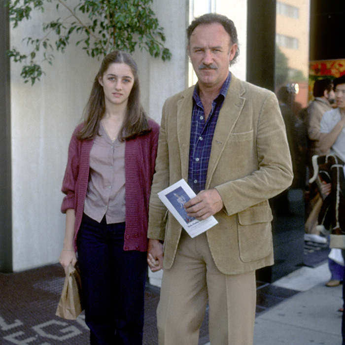 Gene Hackman and daughter holding hands on a sidewalk, near a potted plant, outside a building. Gene Hackman and daughter holding hands on a sidewalk, near a potted plant, outside a building.