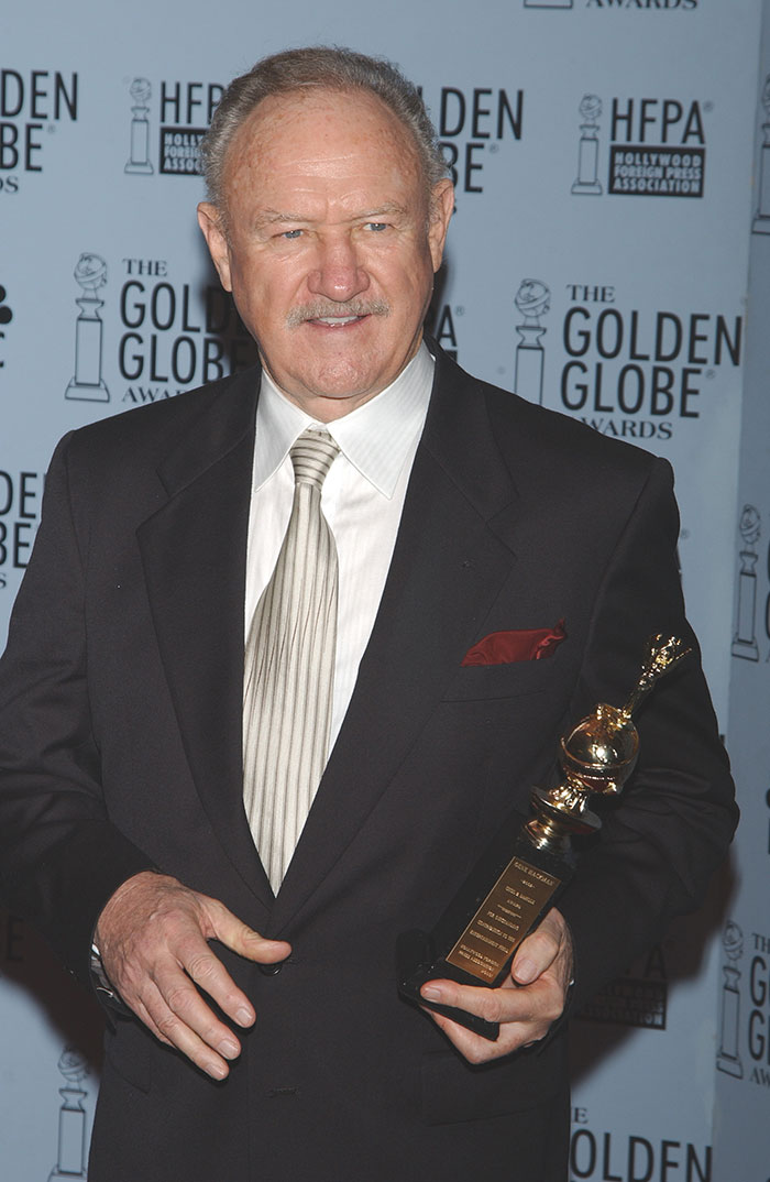 Gene Hackman at Golden Globe Awards, holding a trophy, wearing a suit with a striped tie. Gene Hackman at Golden Globe Awards, holding a trophy, wearing a suit with a striped tie.