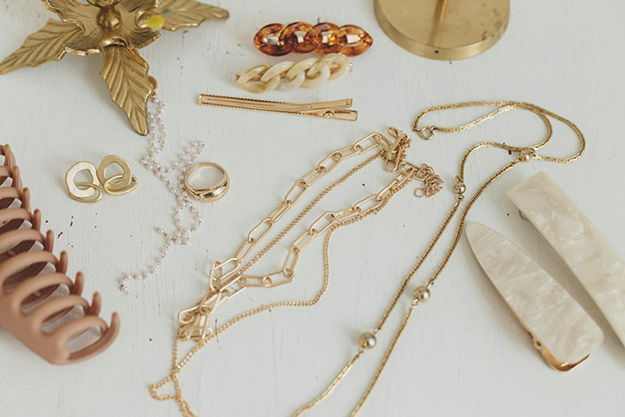 Assorted jewelry items and hair accessories on a white surface, including necklaces and earrings. Assorted jewelry items and hair accessories on a white surface, including necklaces and earrings.