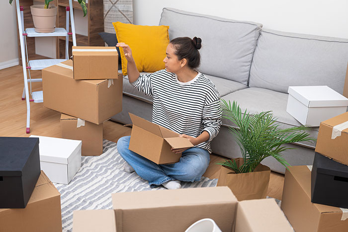 Woman packing unmarked boxes in living room, preparing to move out. Woman packing unmarked boxes in living room, preparing to move out.