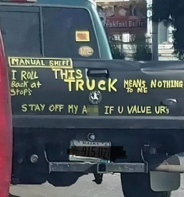 Truck with humorous sign fail message about manual shifting and tailgating.