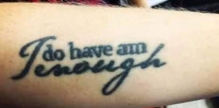 Tattoo text fail with the words "I do have am enough" on a forearm.