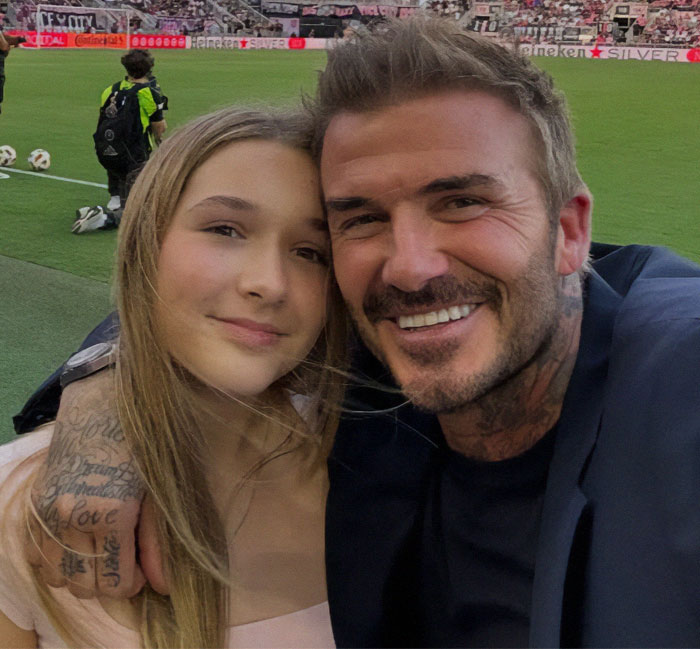 Father and daughter smiling at a soccer stadium, highlighting family bonding moments. Father and daughter smiling at a soccer stadium, highlighting family bonding moments.