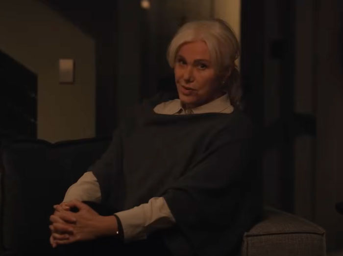 A person sitting on a chair in dim lighting, hands clasped, conveying a contemplative mood. A person sitting on a chair in dim lighting, hands clasped, conveying a contemplative mood.