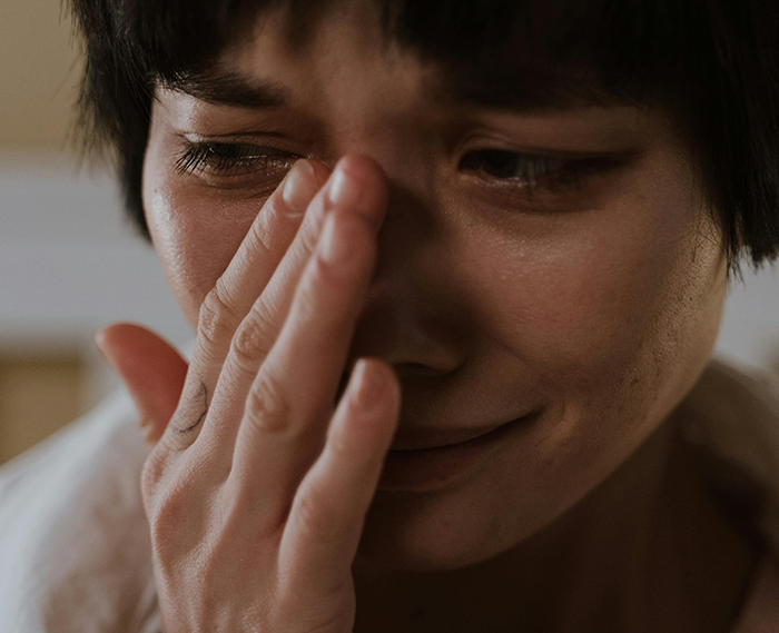 A woman looking upset, covering her face with her hand, highlighting the challenges in a marital space-sharing issue. A woman looking upset, covering her face with her hand, highlighting the challenges in a marital space-sharing issue.
