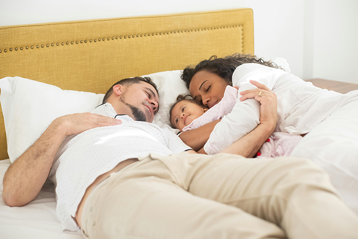 Family cuddling on a bed, highlighting wife and toddler bonding time. Family cuddling on a bed, highlighting wife and toddler bonding time.
