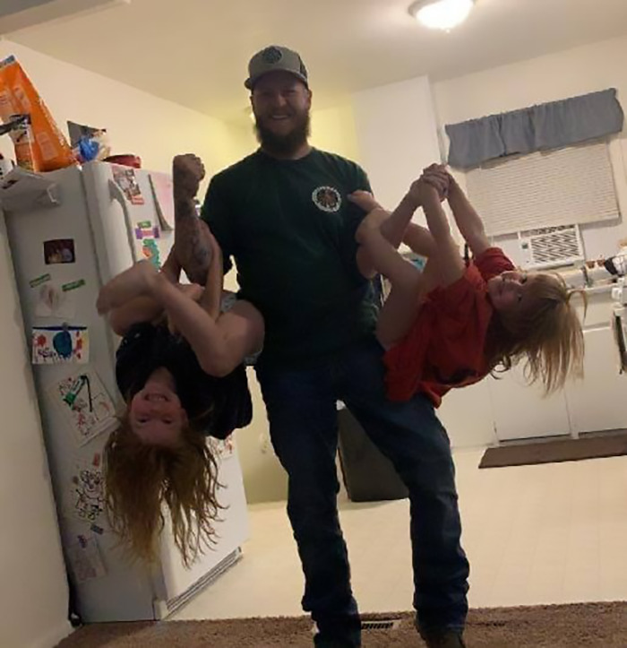 Man playfully lifting children in a kitchen setting. Man playfully lifting children in a kitchen setting.