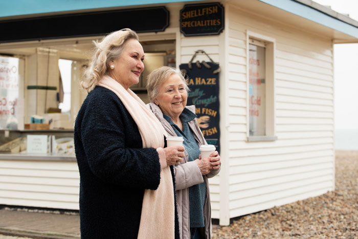 Two women enjoying coffee outside a seafood shop, illustrating a moment related to uninvited dinner guest dynamics. Two women enjoying coffee outside a seafood shop, illustrating a moment related to uninvited dinner guest dynamics.