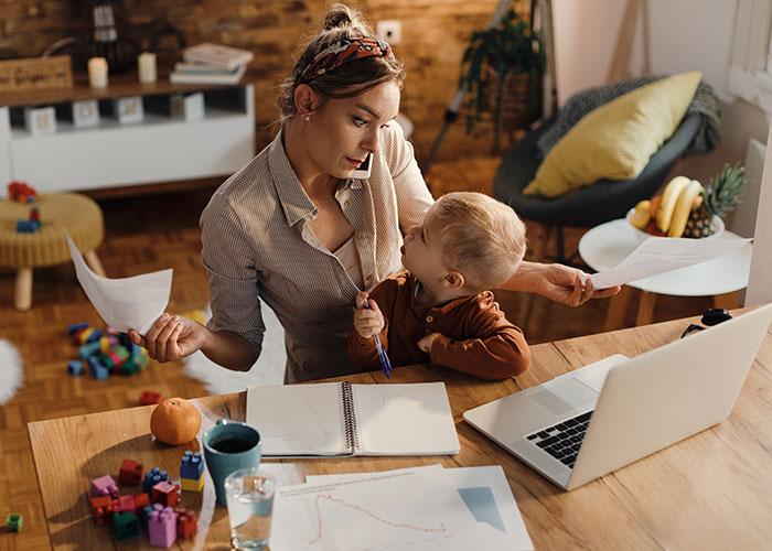 Woman balancing work and motherhood at a home office, representing challenges in marriage and job decisions. Woman balancing work and motherhood at a home office, representing challenges in marriage and job decisions.