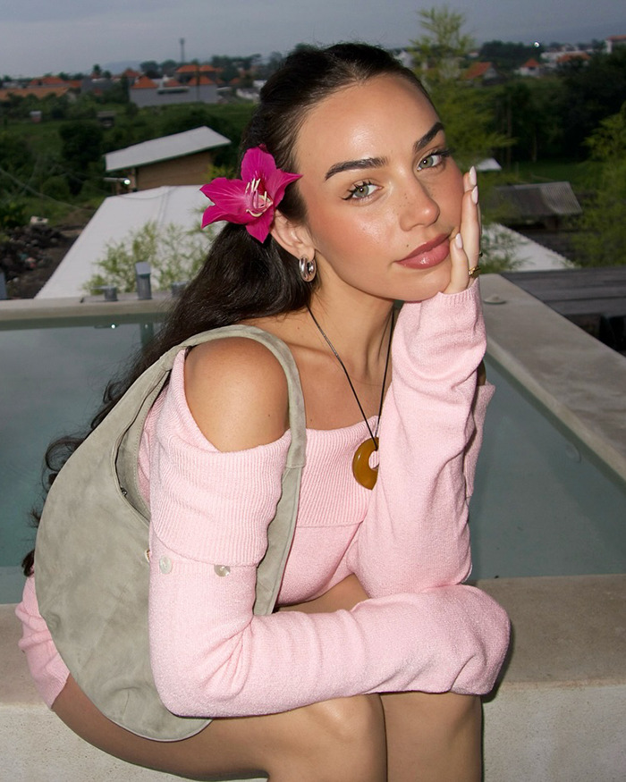 Influencer wearing a pink dress by a poolside with a flower in her hair. Influencer wearing a pink dress by a poolside with a flower in her hair.