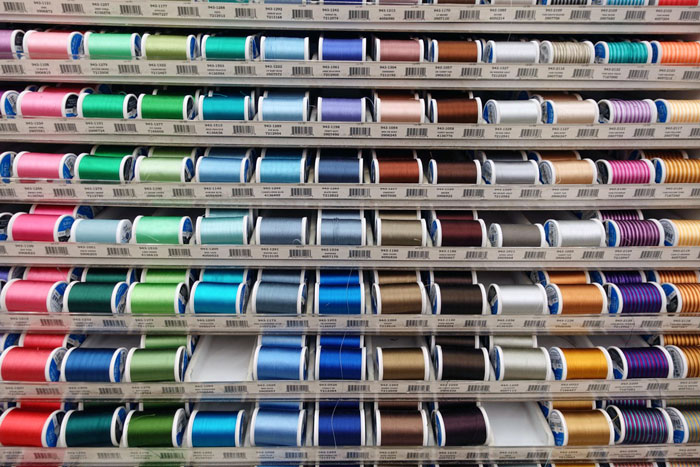 Colorful sewing thread spools on display at a Joann fabric and craft retailer. Colorful sewing thread spools on display at a Joann fabric and craft retailer.