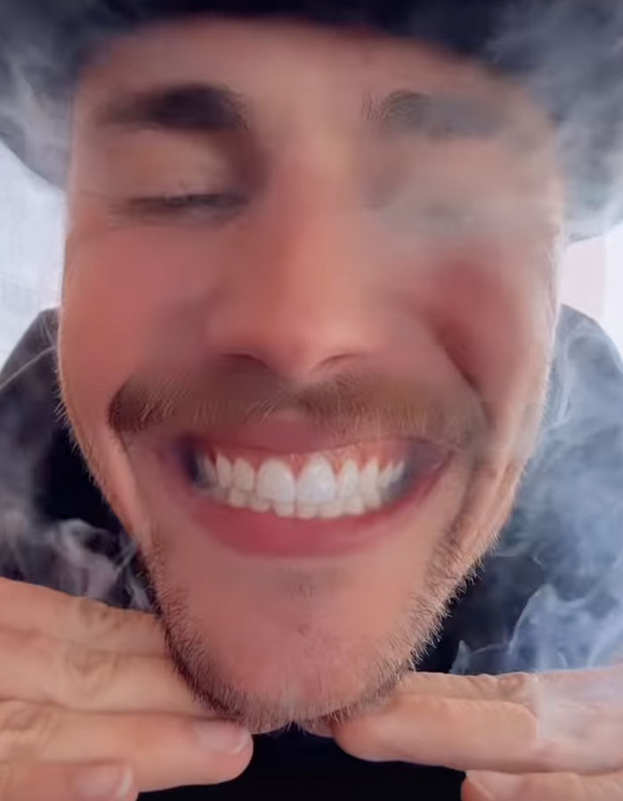 Person smiling with smoke surrounding their face, creating a hazy effect. Person smiling with smoke surrounding their face, creating a hazy effect.