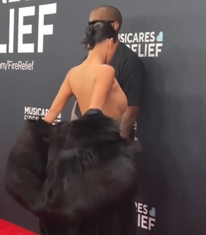 Bianca Censori on the red carpet, wearing a black outfit, with Kanye West in the background. Bianca Censori on the red carpet, wearing a black outfit, with Kanye West in the background.