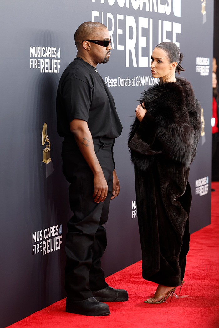 Kanye and Bianca on Grammys red carpet, Kanye in black outfit, Bianca in fur coat, standing in front of a MusiCares sign. Kanye and Bianca on Grammys red carpet, Kanye in black outfit, Bianca in fur coat, standing in front of a MusiCares sign.