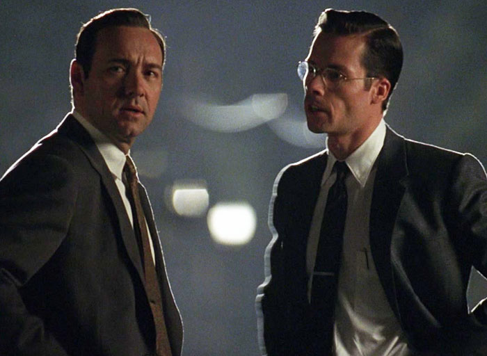 Guy Pearce and Kevin Spacey in suits having a conversation outdoors at night. Guy Pearce and Kevin Spacey in suits having a conversation outdoors at night.