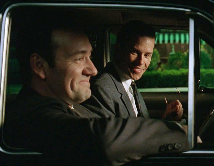 Kevin Spacey and Guy Pearce conversing inside a car, one with a slight smile in L.A. Confidential Kevin Spacey and Guy Pearce conversing inside a car, one with a slight smile in L.A. Confidential