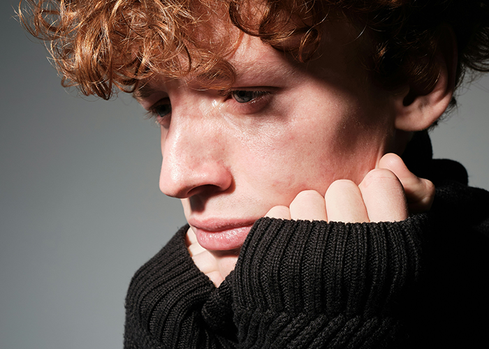 Young person looking sad, wearing a black sweater, reflecting the topic of family and LGBTQ+ acceptance. Young person looking sad, wearing a black sweater, reflecting the topic of family and LGBTQ+ acceptance.