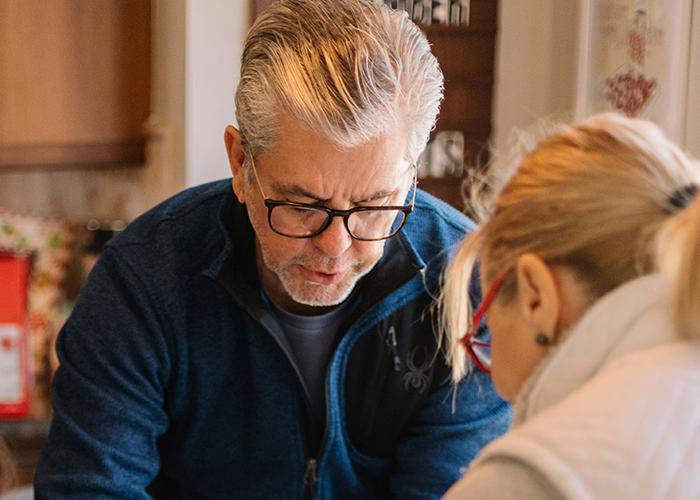 Man in glasses, blue sweater focused on task with woman, related to family and LGBTQ+ topics. Man in glasses, blue sweater focused on task with woman, related to family and LGBTQ+ topics.