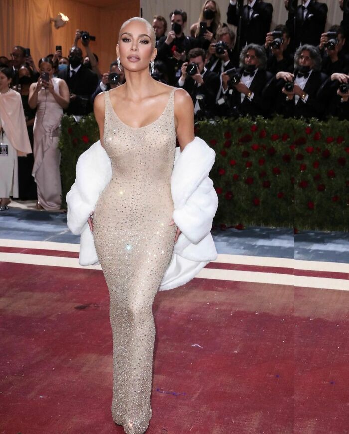 Kim Kardashian at the Met Gala wearing an ultra-tight corset gown, surrounded by photographers. Kim Kardashian at the Met Gala wearing an ultra-tight corset gown, surrounded by photographers.