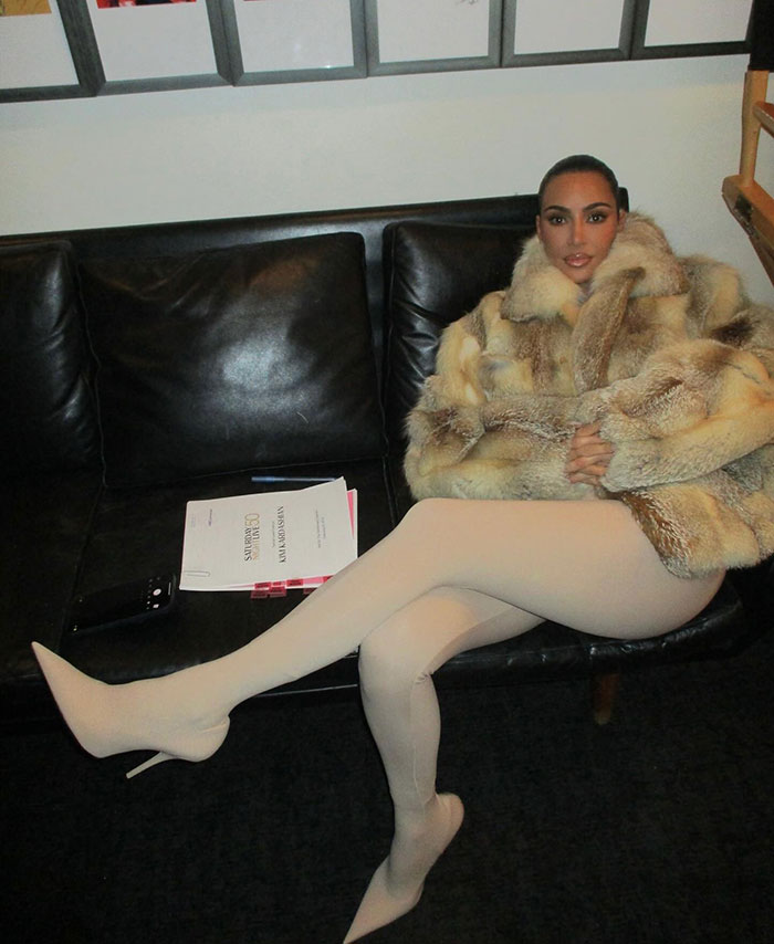 Woman in fur coat seated on a black couch next to documents, embodying modern style and elegance indoors. Woman in fur coat seated on a black couch next to documents, embodying modern style and elegance indoors.