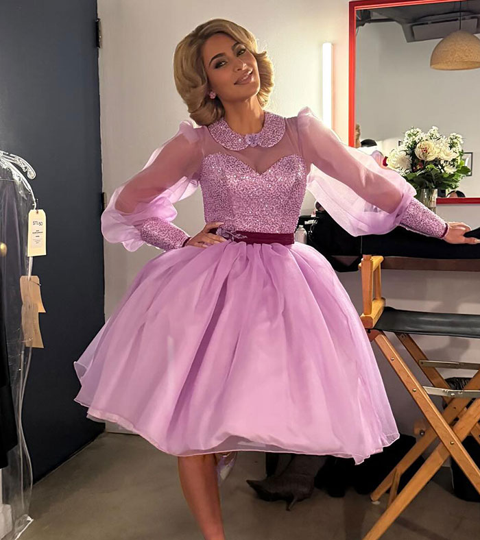 Woman in a lilac dress posing in a dressing room setting. Woman in a lilac dress posing in a dressing room setting.