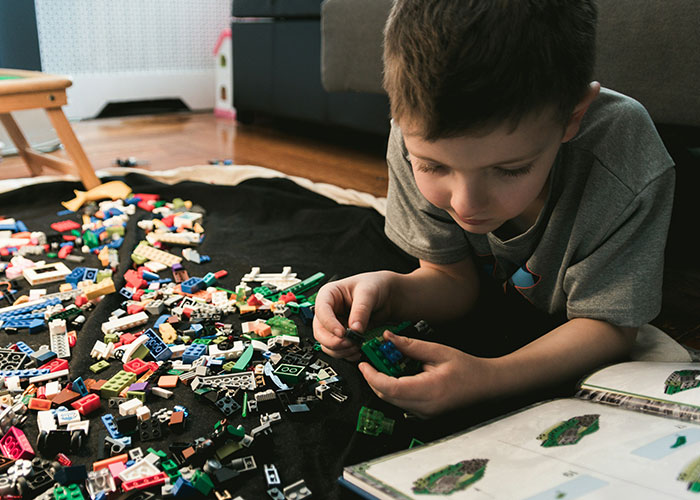 Child playing with toy bricks on the floor, absorbed in building from a book. Child playing with toy bricks on the floor, absorbed in building from a book.