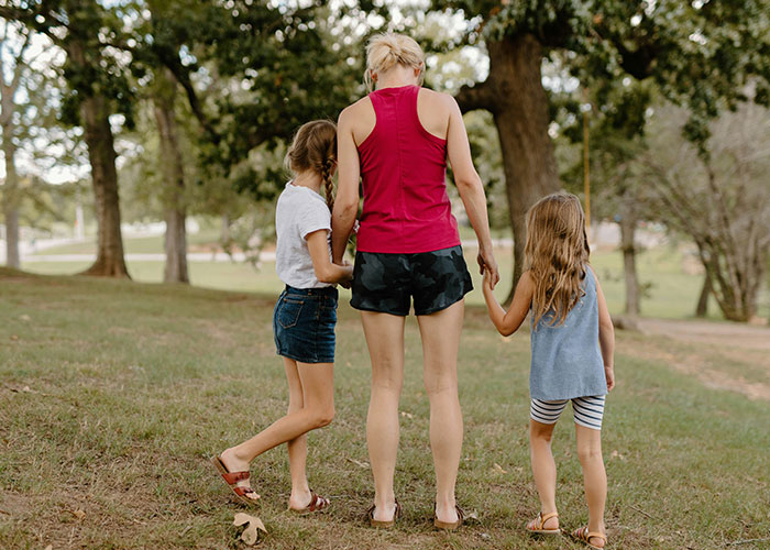 A mother with two kids walking in a park, holding hands, surrounded by trees. A mother with two kids walking in a park, holding hands, surrounded by trees.