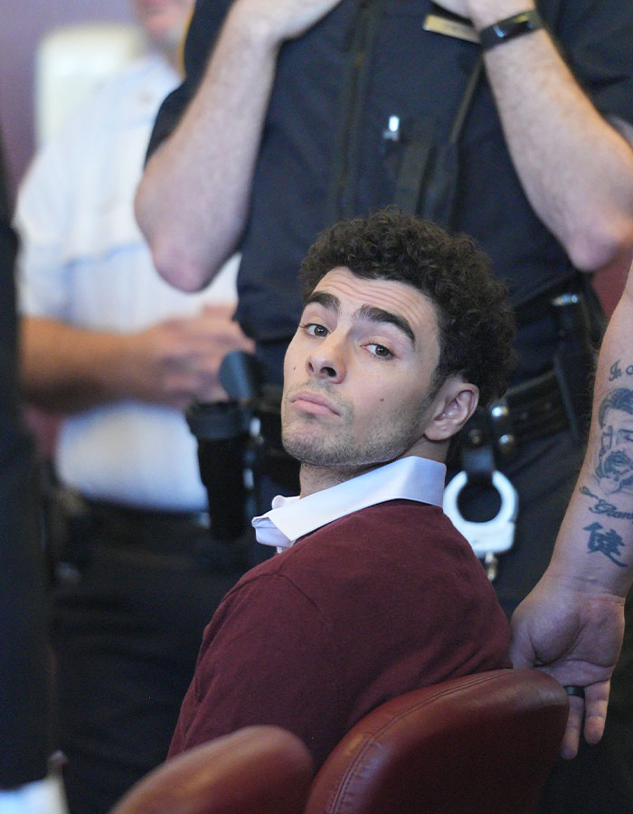 Man in courtroom setting surrounded by officers, related to Luigi Mangione's public statement and reactions. Man in courtroom setting surrounded by officers, related to Luigi Mangione's public statement and reactions.