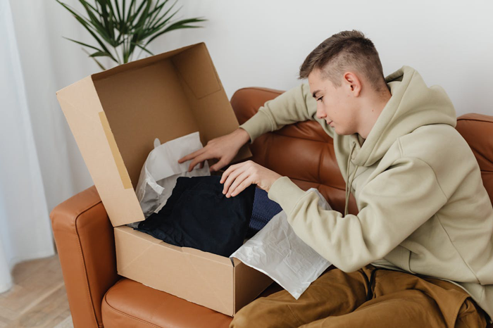 Guy finds a creepy box in his girlfriend's wardrobe while sitting on a brown sofa, looking curious. Guy finds a creepy box in his girlfriend's wardrobe while sitting on a brown sofa, looking curious.