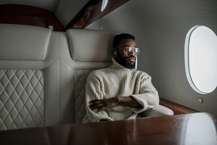 Man in a white sweater sitting beside an aircraft window, looking contemplative. Man in a white sweater sitting beside an aircraft window, looking contemplative.