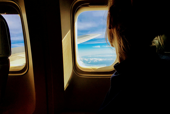 Person viewing clouds from an airplane seat through a window, highlighting the desire for a window seat. Person viewing clouds from an airplane seat through a window, highlighting the desire for a window seat.
