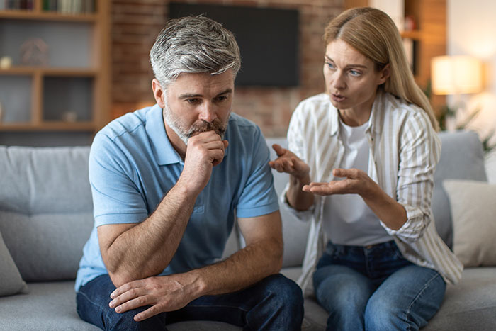 Man and woman having a serious conversation on a couch, emotions tense, discussing living arrangements with stepdad. Man and woman having a serious conversation on a couch, emotions tense, discussing living arrangements with stepdad.