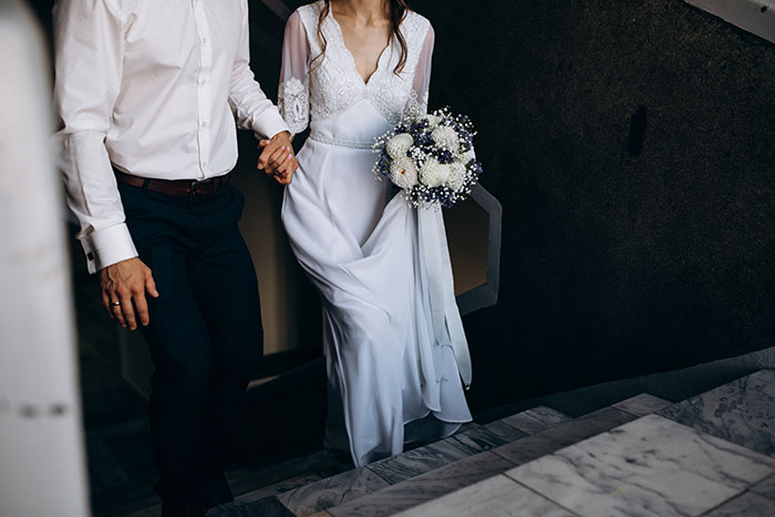 Man in white shirt and woman in wedding dress with bouquet ascending stairs, related to wedding dropout due to fiancée's attractiveness. Man in white shirt and woman in wedding dress with bouquet ascending stairs, related to wedding dropout due to fiancée's attractiveness.