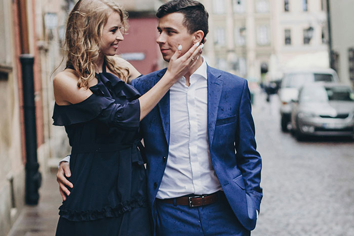 A man and woman smiling at each other on a cobblestone street, dressed in formal attire; focus on wedding context. A man and woman smiling at each other on a cobblestone street, dressed in formal attire; focus on wedding context.