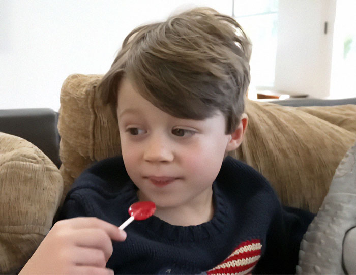 Young boy with a lollipop sitting on a couch. Autism breakthrough helps nonverbal child speak. Young boy with a lollipop sitting on a couch. Autism breakthrough helps nonverbal child speak.