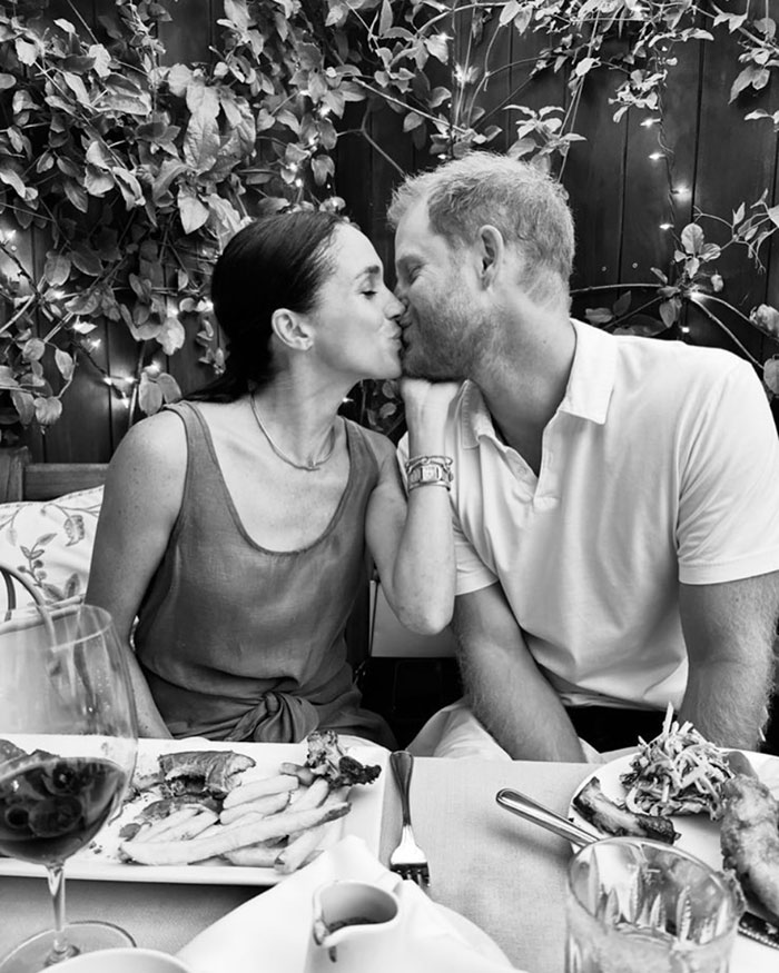 A couple kissing at a dining table surrounded by plants, enjoying a meal together. A couple kissing at a dining table surrounded by plants, enjoying a meal together.