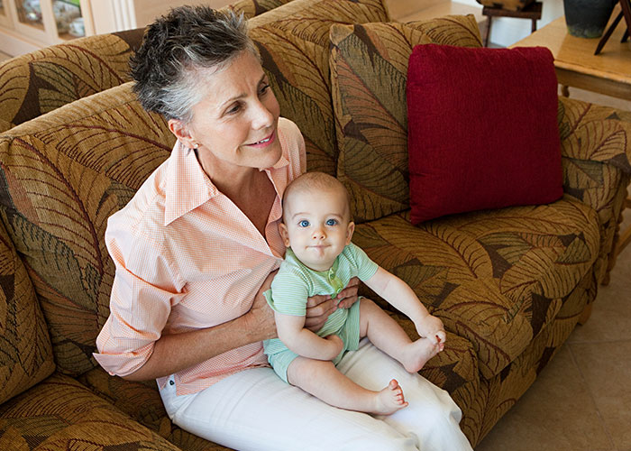 Grandmother with grandson on a patterned sofa, both smiling, showcasing family dynamics and relationships. Grandmother with grandson on a patterned sofa, both smiling, showcasing family dynamics and relationships.