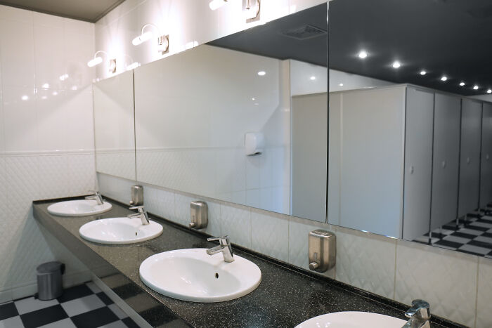Public restroom sinks with mirrors reflecting common hygiene habits.
