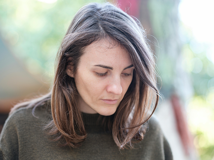 Woman outdoors looking down, related to an airplane incident involving an angry passenger and a toddler. Woman outdoors looking down, related to an airplane incident involving an angry passenger and a toddler.