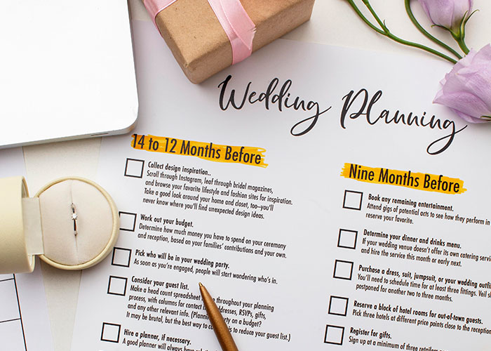 Wedding planning checklist with a pen, gift box, and flowers, focusing on preparation details. Wedding planning checklist with a pen, gift box, and flowers, focusing on preparation details.
