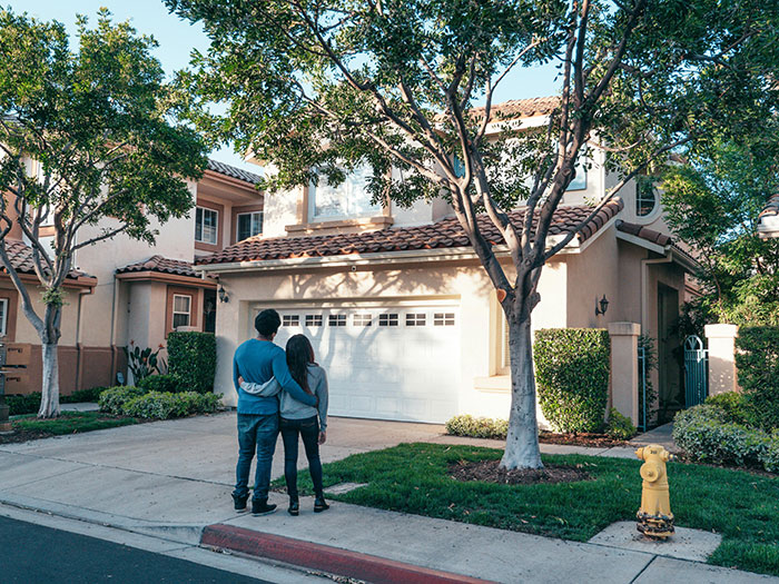 Couple standing in front of garage, contemplating neighbor parking car unauthorized in driveway. Couple standing in front of garage, contemplating neighbor parking car unauthorized in driveway.