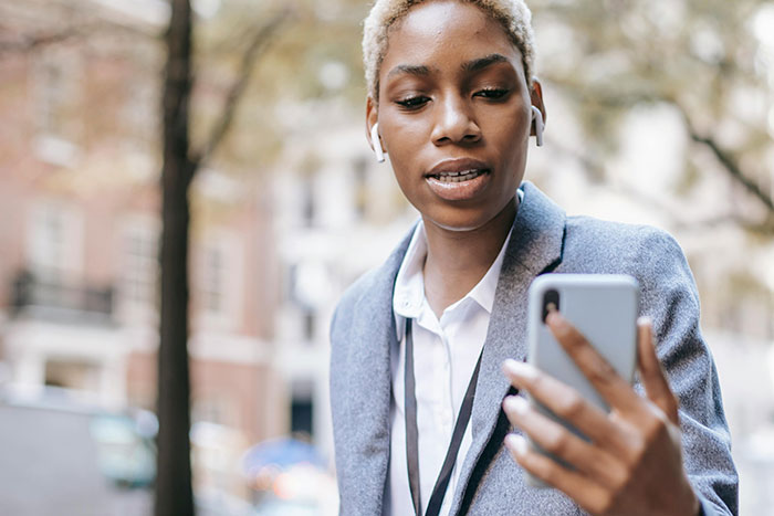 Person in a blazer looking at a phone outdoors, possibly addressing a neighbor parking car unauthorized issue. Person in a blazer looking at a phone outdoors, possibly addressing a neighbor parking car unauthorized issue.