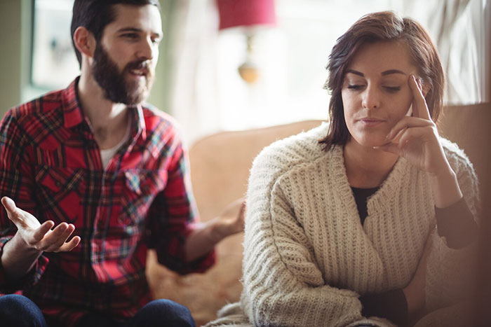 Man in plaid shirt discussing unauthorized parking while woman in a sweater appears frustrated at home. Man in plaid shirt discussing unauthorized parking while woman in a sweater appears frustrated at home.