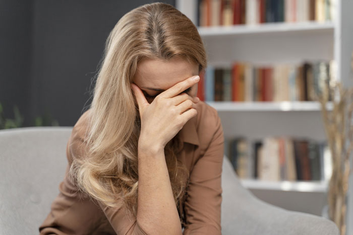 Woman sitting in a chair, appearing frustrated, possibly due to a neighbour's unchanged WiFi password, in a room with bookshelves. Woman sitting in a chair, appearing frustrated, possibly due to a neighbour's unchanged WiFi password, in a room with bookshelves.