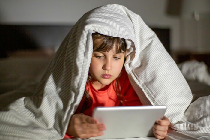 Child under blanket using tablet, highlighting neighbor won't change WiFi password issue. Child under blanket using tablet, highlighting neighbor won't change WiFi password issue.