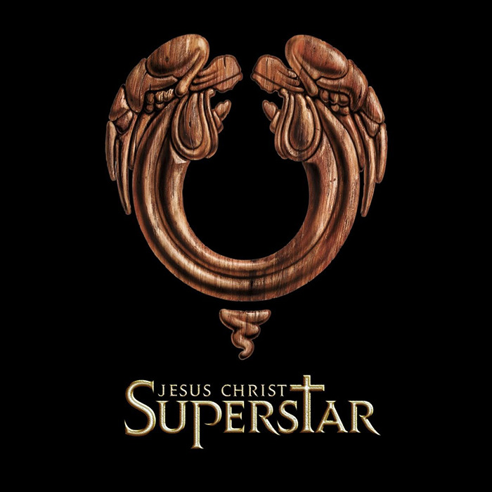 Jesus Christ Superstar logo featuring a wooden angelic design on a black background. Jesus Christ Superstar logo featuring a wooden angelic design on a black background.
